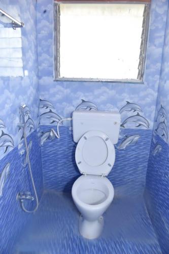 a blue bathroom with a toilet and a window at Samarth Villa in Akalkot