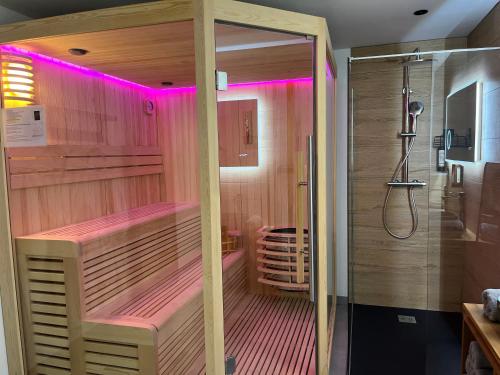 une salle de bain avec une douche éclairée en rose dans l'établissement La Biche, à Saint-Martin-sur-le-Chambre