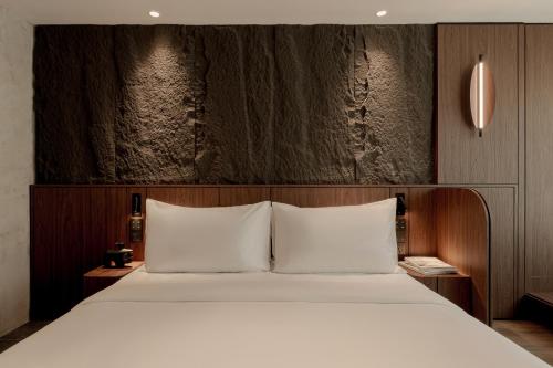 ein Schlafzimmer mit einem großen Bett und weißen Kissen in der Unterkunft The Cara Hotel in Kota Kinabalu