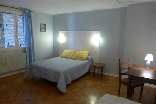 een slaapkamer met een bed met gele kussens en een tafel bij Grain d'orge in Aubepierre-sur-Aube
