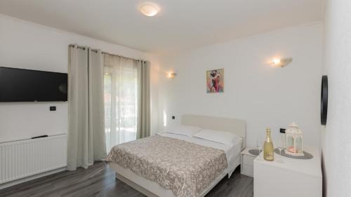 een witte slaapkamer met een bed en een flatscreen-tv bij Villa FourM - Makarska by Villas Guide in Novak