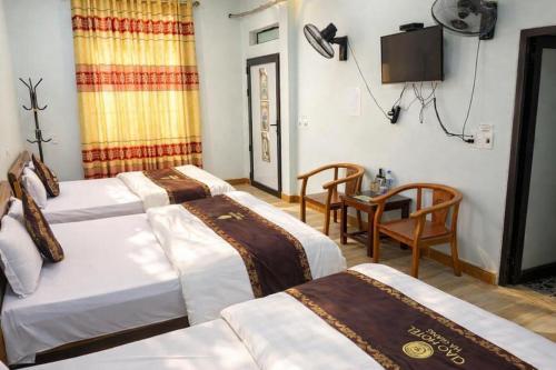 a hotel room with three beds and a television at Ciao Homestay in Dồng Văn