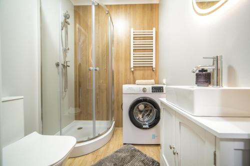 a bathroom with a shower and a washing machine at Willa na Dębowej in Katowice