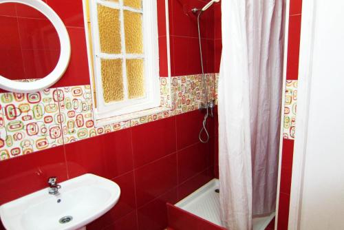 a bathroom with a toilet, sink, and mirror at Duas Nações Guest House in Porto