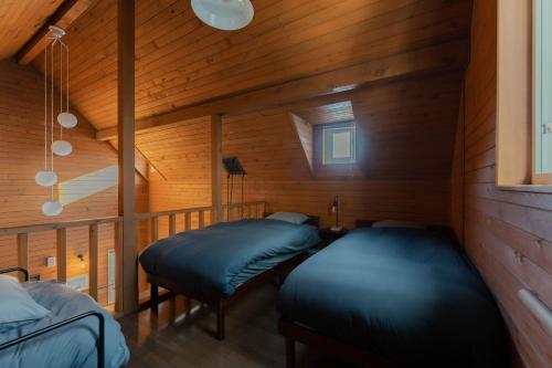 twee bedden in een kamer met houten wanden bij Mokurie in Teshikaga