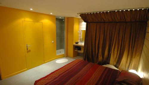 ein Schlafzimmer mit einem Bett und einer gelben Tür sowie ein Badezimmer in der Unterkunft Les Ô du Panier in Marseille