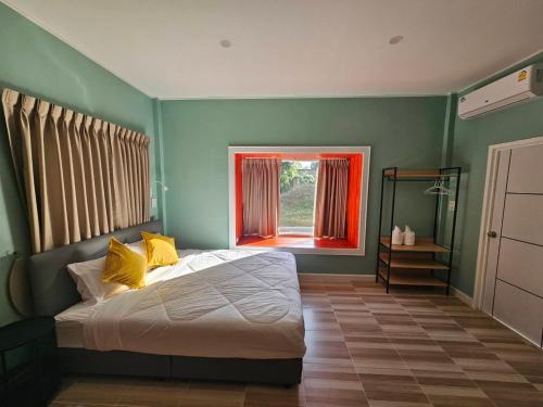 een slaapkamer met groene muren en een bed met gele kussens bij คุณเก้า รีสอร์ท in Non Sa-at