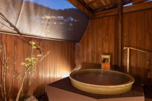 a bathroom with a large tub on a wooden wall at Kokuya in Shibukawa
