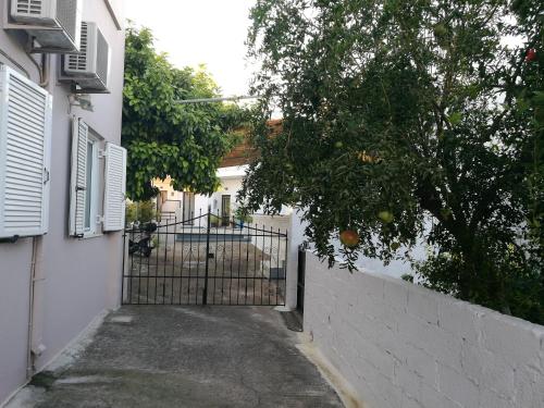 a gate to a white house with an orange tree at Pension Annoula in Archangelos