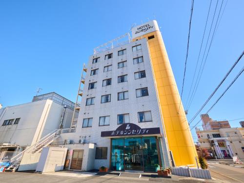 a tall white building with a yellow tower at Hotel Sincerity kani in Kani