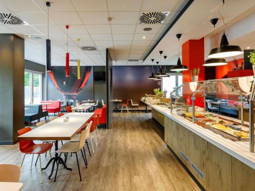 a restaurant with tables and chairs and a buffet at ibis Hotel Frankfurt Airport in Kelsterbach