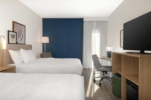 a hotel room with two beds and a flat screen tv at Spark By Hilton Montreal Midtown in Montréal
