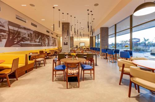 ein Restaurant mit Tischen, Stühlen und Fenstern in der Unterkunft Hampton By Hilton Caraguatatuba Serramar in Caraguatatuba