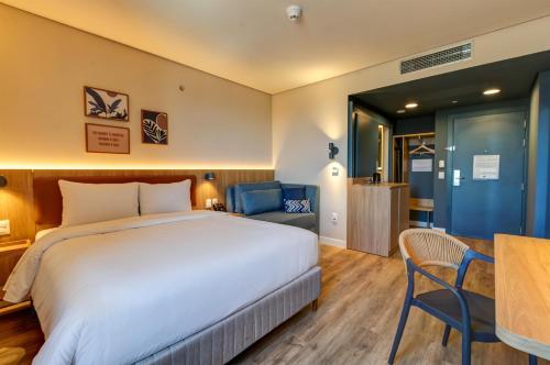 ein Hotelzimmer mit einem großen Bett und einem Tisch in der Unterkunft Hampton By Hilton Caraguatatuba Serramar in Caraguatatuba