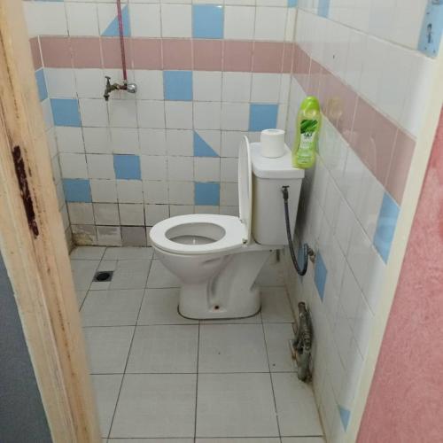 une salle de bain avec toilettes dans une pièce carrelée dans l'établissement Chez Bernard, à Libreville