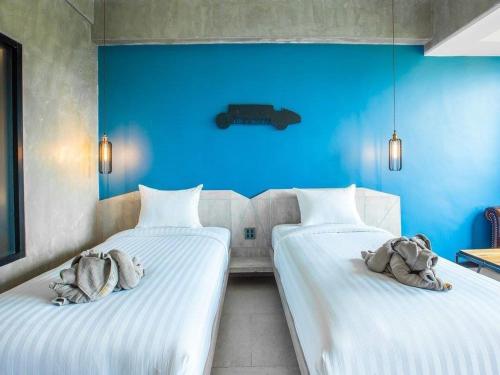 two beds in a room with blue walls at Loft Mania Boutique Hotel in Chumphon