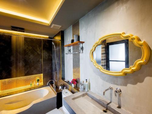 La salle de bains est pourvue d'une baignoire, d'un lavabo et d'un miroir. dans l'établissement Loft Mania Boutique Hotel, à Chumpon