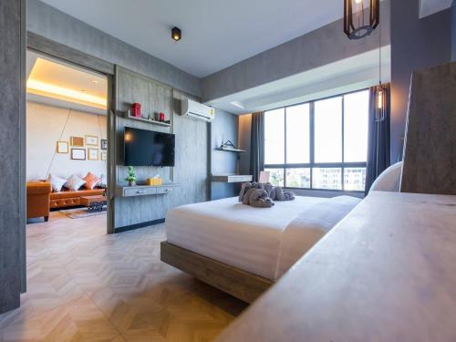 a bedroom with a large bed and a television at Loft Mania Boutique Hotel in Chumphon