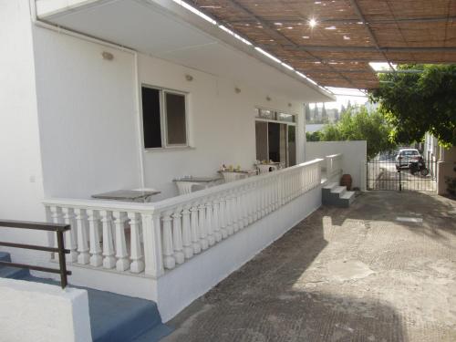 a white house with a white railing and a balcony at Pension Annoula in Archangelos