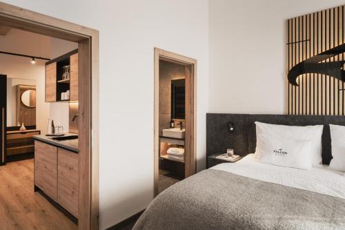 a bedroom with a large bed and a bathroom at Falcon Suites Pure - Summercard included in Kaprun