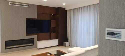 een woonkamer met een flatscreen-tv aan de muur bij Interlace penthouse with swimming pool in Il-Ħamrija