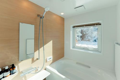 een badkamer met een wit bad en een raam bij Mokurie in Teshikaga