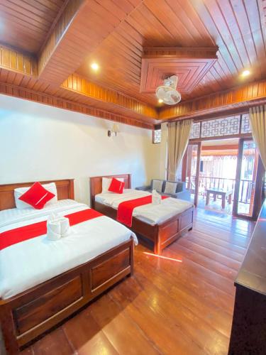 een kamer met twee bedden en een bank erin bij Villa Xiengthong Garden View in Luang Prabang