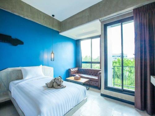 a bedroom with blue walls and a bed with a stuffed animal on it at Loft Mania Boutique Hotel in Chumphon