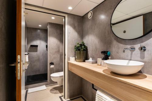 een badkamer met een wastafel, een toilet en een spiegel bij Hotel Maassluis in Maassluis