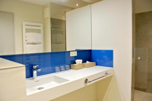 ein Badezimmer mit Waschbecken und Spiegel in der Unterkunft Bernsteinsee Hotel&Ferien in Sassenburg