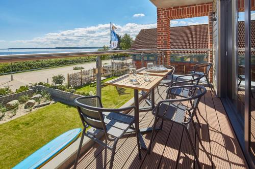 a deck with a table and chairs on a balcony at Ostsee-Strandhaus-Holnis in Glücksburg