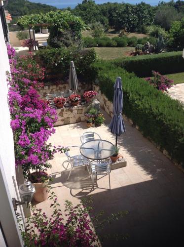 a patio with a table and two umbrellas and flowers at Apartments Villa Ina in Brseč