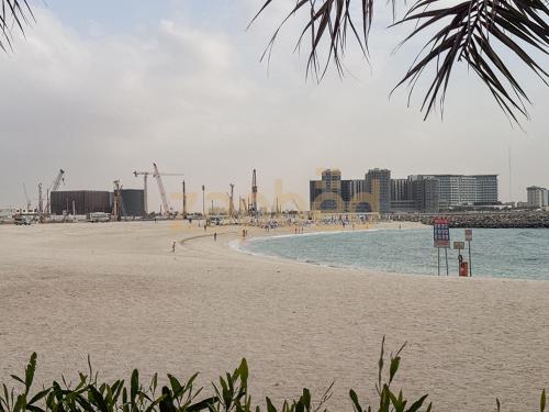 a sandy beach with a city in the background at ZAPBED HOUSE -1 BR In Pacific Tower Al Marjan Island With Beach Access Ras Al Khaimah in Ras al Khaimah