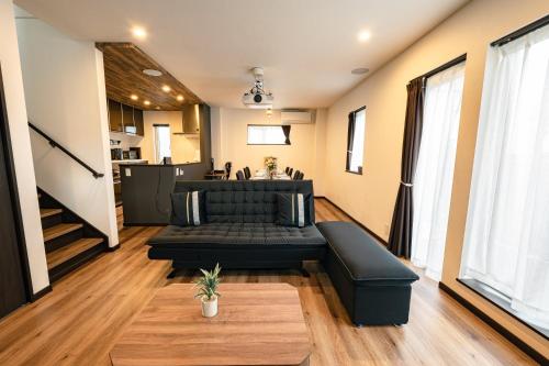 a living room with a black couch and a table at Guest House TEINE Nisimiyanosawa 41 最大11名滞在 無料駐車場2台完備 TEINE Ski Resort車で15分 in Sapporo