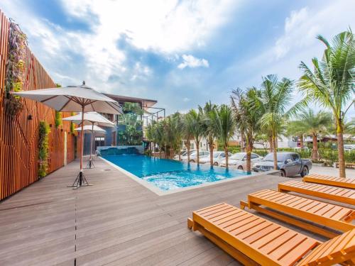 a pool with chairs and an umbrella on a deck at Loft Mania Boutique Hotel in Chumphon