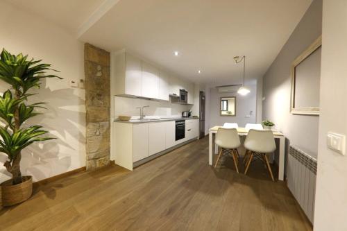 une cuisine avec des armoires blanches et une table et des chaises dans l'établissement Bravissimo Força 17, Barri Vell apartments, à Gérone
