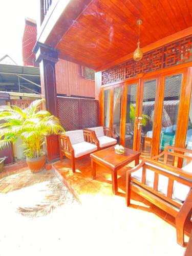 een veranda met banken en een tafel en stoelen bij Villa Xiengthong Garden View in Luang Prabang