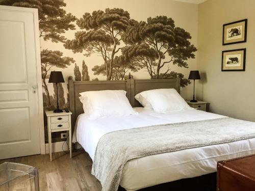 a bedroom with a bed and trees on the wall at Villa la Ruche in La Baule