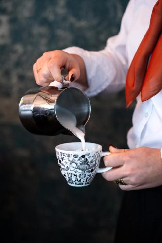 瓦赫宁根威里德酒店的一个人用勺子往杯子里倒牛奶。