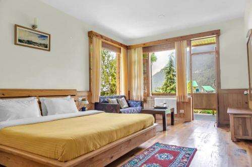 a bedroom with a bed and a couch and windows at The Green Mountain Lodge in Manāli