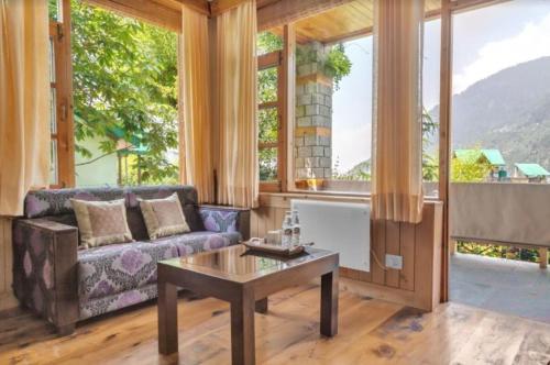un soggiorno con un divano e un tavolo di The Green Mountain Lodge a Manāli