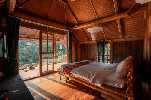 a bedroom with a bed in a room with windows at Pù Luông Ecolodge in Pu Luong