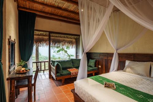 a bedroom with a canopy bed and a chair at Pù Luông Ecolodge in Pu Luong