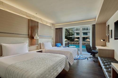 a hotel room with two beds and a balcony at Le Meridien Goa, Calangute in Calangute