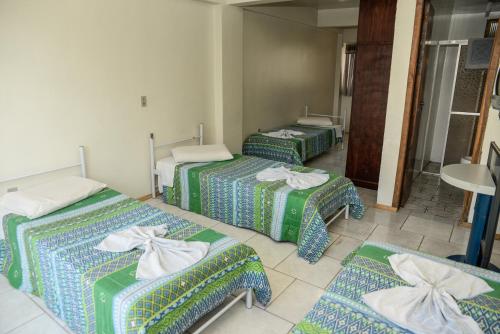 un grupo de 3 camas en una habitación en Hotel Piacenza, en Caxias do Sul