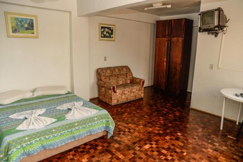 a bedroom with a bed and a chair at Hotel Piacenza in Caxias do Sul