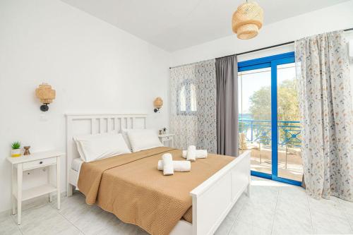 een witte slaapkamer met een bed en een groot raam bij Anna's view Stegna in Vrachonisída touArchangélou