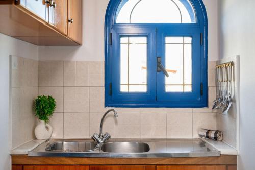 een keuken met een wastafel en een blauw raam bij Anna's view Stegna in Vrachonisída touArchangélou