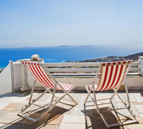 - deux chaises assises sur un balcon avec vue sur l'océan dans l'établissement Sea View Exclusive Studios - Tinos, à Agios Ioannis