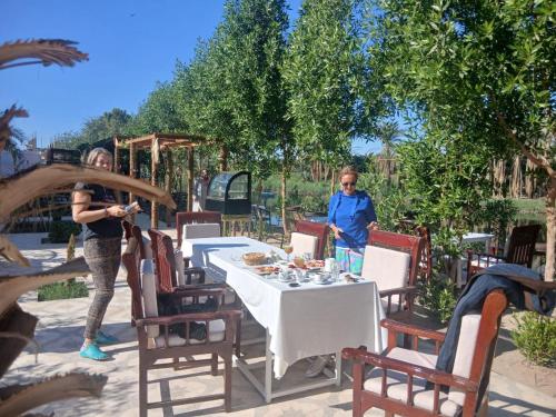 zwei Frauen stehen neben einem Tisch und Stühlen in der Unterkunft Lake House Hotel in Luxor